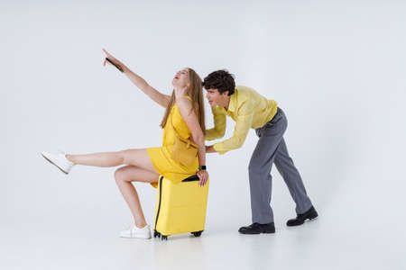 Handsome man giving his girlfriend ride on travel suitcaseの写真素材