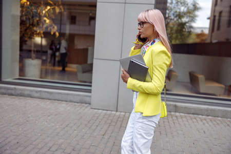Female pedestrian speaking on mobile phone on her wayの写真素材