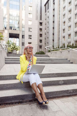 Overjoyed lady having a call during outdoor work with laptopの写真素材