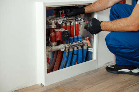 Cropped shot of technician, plumber in protective gloves checking water pipes and meter counterの写真素材