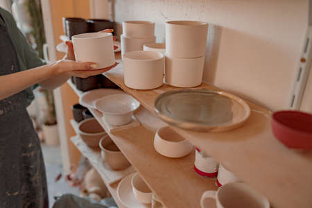 Photo of handmade clay crockery at shelf in workroomの写真素材