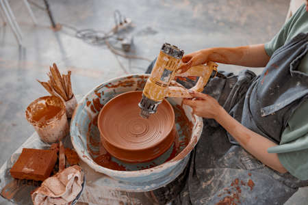 Skillful craftswoman making bowl in pottery workshopの写真素材