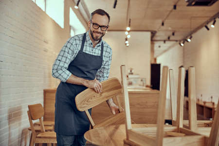 Joyful cafe owner preparing chairs for customersの写真素材
