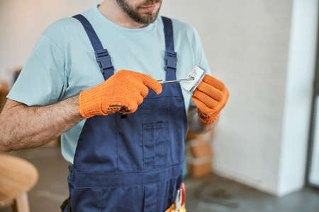 Young man in work gloves repairing electrical socketの写真素材