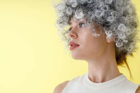 Pretty young woman in wig standing in studio