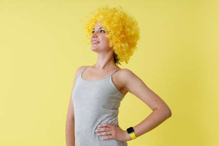Joyful young woman in yellow wig standing in studioの写真素材