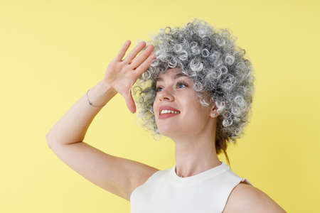 Cheerful young woman in wig standing in studioの写真素材