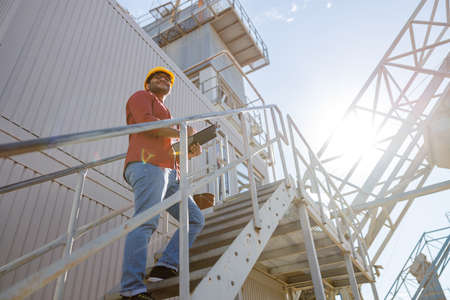 Happy African engineer standing at industrial siteの写真素材