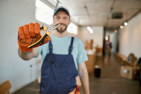 Male worker in work gloves holding pliersの写真素材