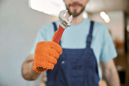Male worker in work gloves holding wrenchの写真素材