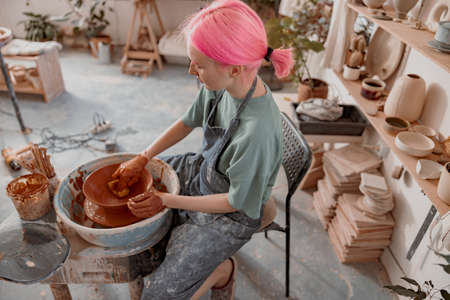 Female crafter making clay dishes in pottery roomの写真素材