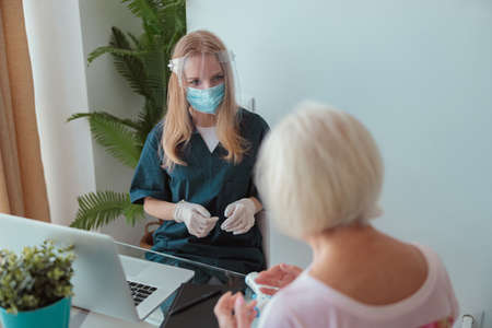 Healthcare specialist checking aged female at homeの写真素材