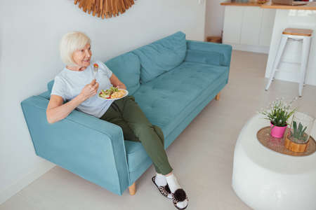 Good looking aged woman eating home food indoorsの写真素材