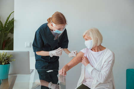 Senior woman getting vaccination at her homeの写真素材