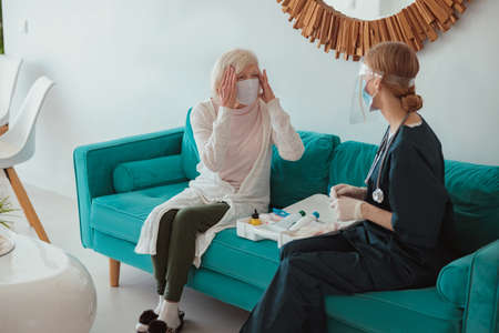 Nurse checking health of senior woman in living roomの写真素材