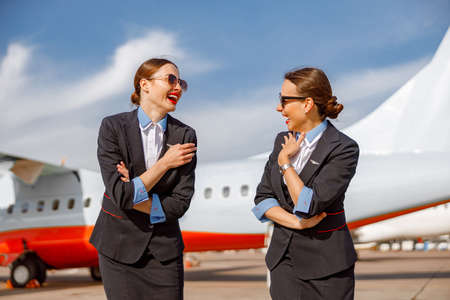 Cheerful women stewardesses chatting and laughing at airportの写真素材