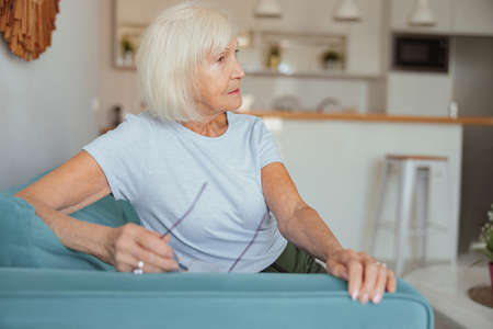 Pensioner female sitting on sofa at home