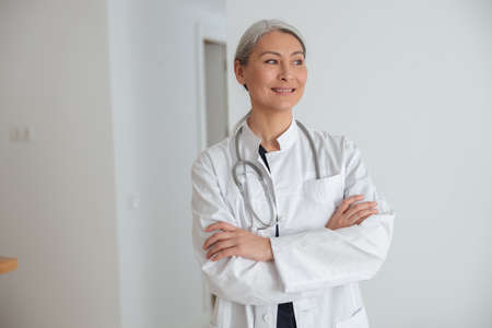 Mature woman physician standing in hall of the hospitalの写真素材