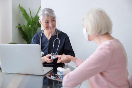 Smiling pediatrician visiting old woman at homeの写真素材
