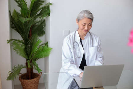 Smiling woman medical specialist working in hospital office at tableの写真素材