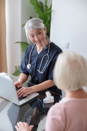 Female doctor visiting elderly patient at homeの写真素材