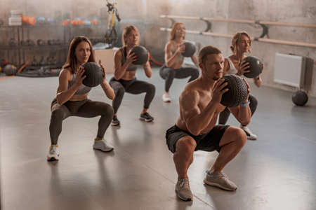 Professional trainer with his clients in gymの写真素材