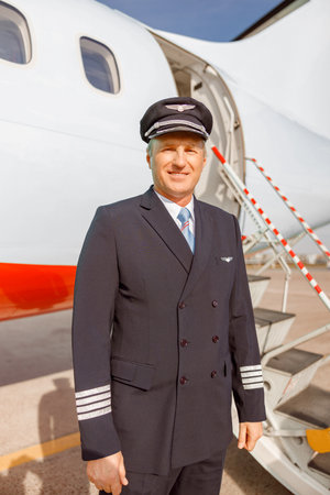 Male aircraft pilot standing near airplane at airportの写真素材