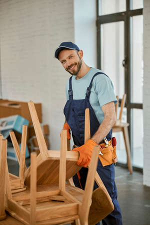 Cheerful young man repairing chair in cafeの写真素材