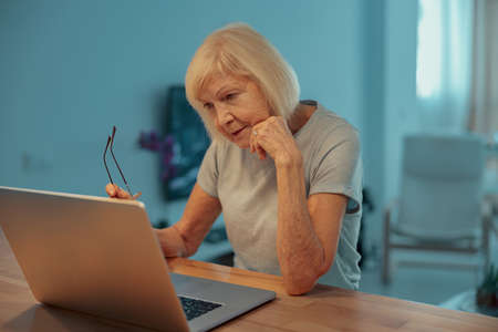Senior woman resting with laptop at homeの写真素材