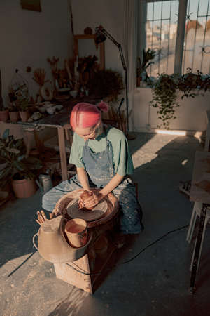 Woman crafter making clay dishes in pottery roomの写真素材