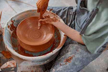Young potter working on potter wheel in workroomの写真素材
