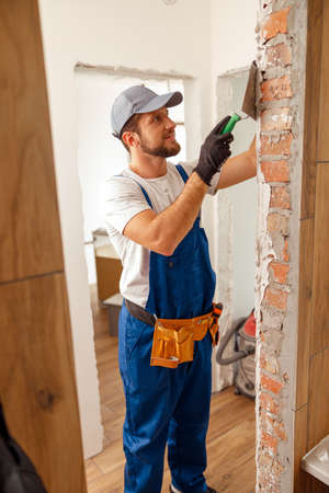 Busy handyman or craftsman applying plaster or filling on the wall, preparing it for paintingの写真素材