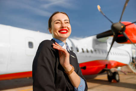 Cheerful woman airline worker standing outdoors at airfieldの写真素材