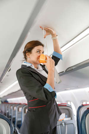 Stewardess demonstrating how to use oxygen mask in aircraft