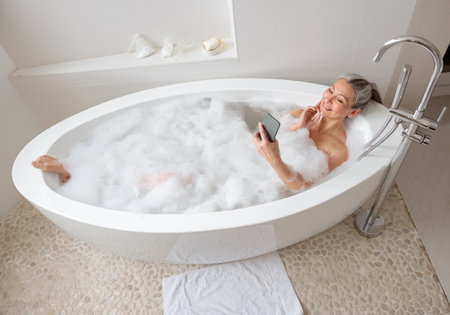 Lady relaxing in the bath and talking on the phoneの写真素材
