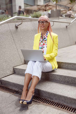 Inspired woman on stair steps using laptopの写真素材