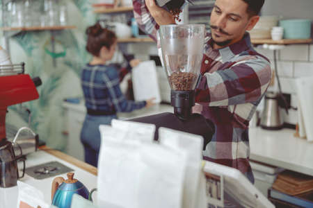 Man grinding coffee beans in electric grinderの写真素材