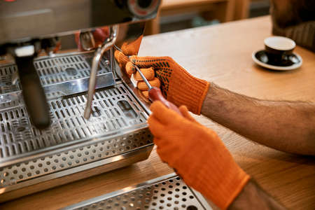 Male hands repairing coffee machine with screwdriverの写真素材