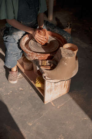 Woman potter shaping clay on pottery wheel in atelierの写真素材