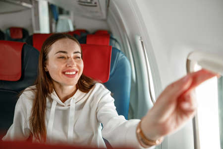 Cheerful young woman looking out the window in airplaneの写真素材