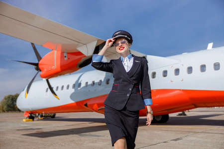 Cheerful woman airline worker standing outdoors at airportの写真素材