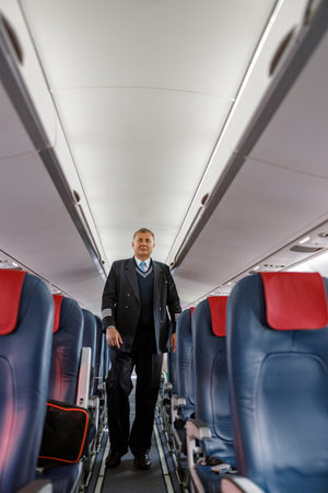 Male aircraft pilot walking down aircraft passenger salonの写真素材