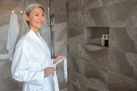 Mature Asian lady untying belt of bathrobeの写真素材