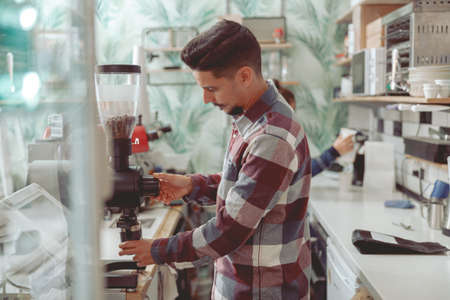 Focused barista male grinding coffee beans in cafe shopの写真素材