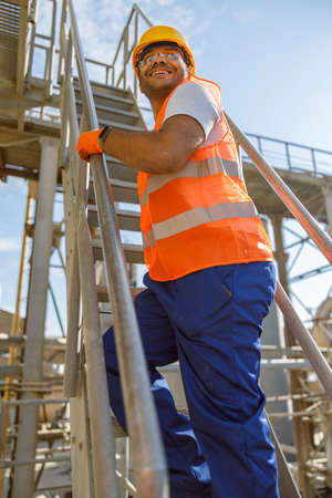 Happy worker dressed in safety equipment inside factoryの写真素材