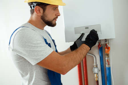 Serious technician setting the new gas boiler for hot water and heatingの写真素材
