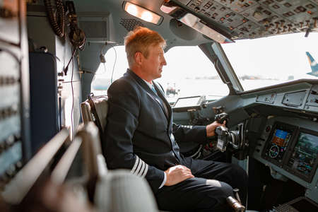 Male pilot sitting in airplane cockpit and waiting for the flightの写真素材