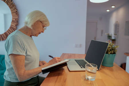 Caucasian elderly female working at laptop indoorsの写真素材