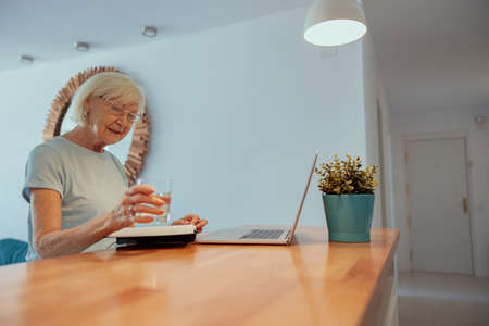 Senior woman sitting at table at homeの写真素材
