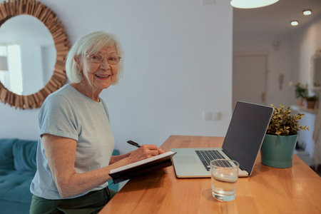 Photo of joyful aged woman with laptop indoorsの写真素材